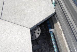 Buzon Pedestals with Spacer Tabs Shown Supporting Irregular Shaped Material and Service Line Concealed by Decking Surface