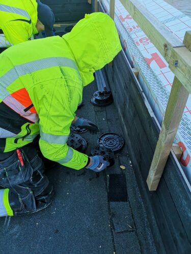 Second worker placing pedestal over slope corrector.
