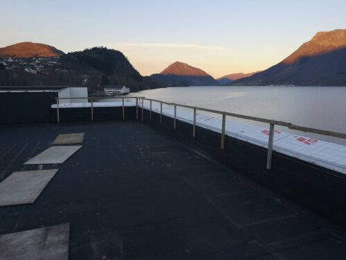 Rooftop showing waterproof membrane and temporary rails before pedestal paver installation.